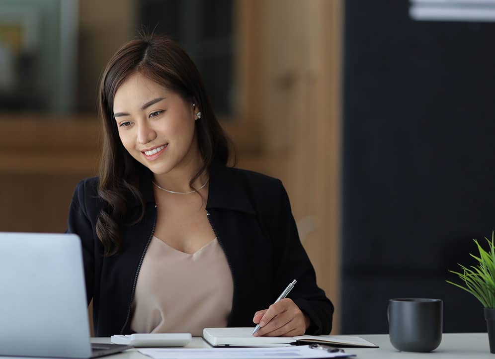 Professional services associate working at laptop in office talking notes