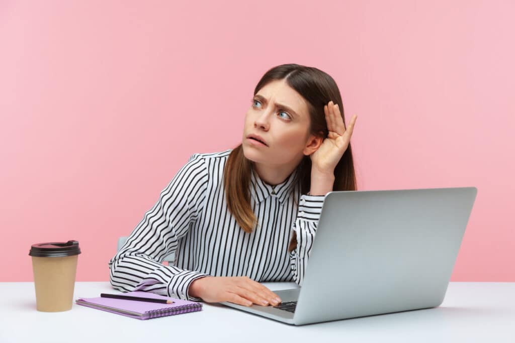 Business woman having trouble hearing audio on laptop